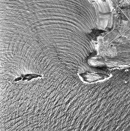 Satellite image showing dramatic wave patterns refracting around islands, demonstrating how swell interacts with coastal features